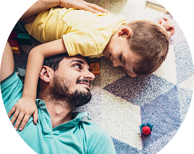 Man and little boy lying on rug with plastic toys 
